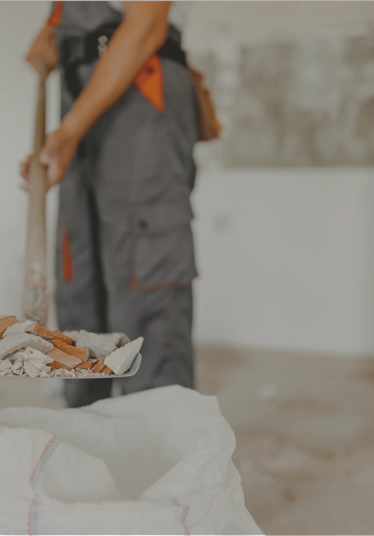 An image of a construction worker using a shovel to pack stones into a sack